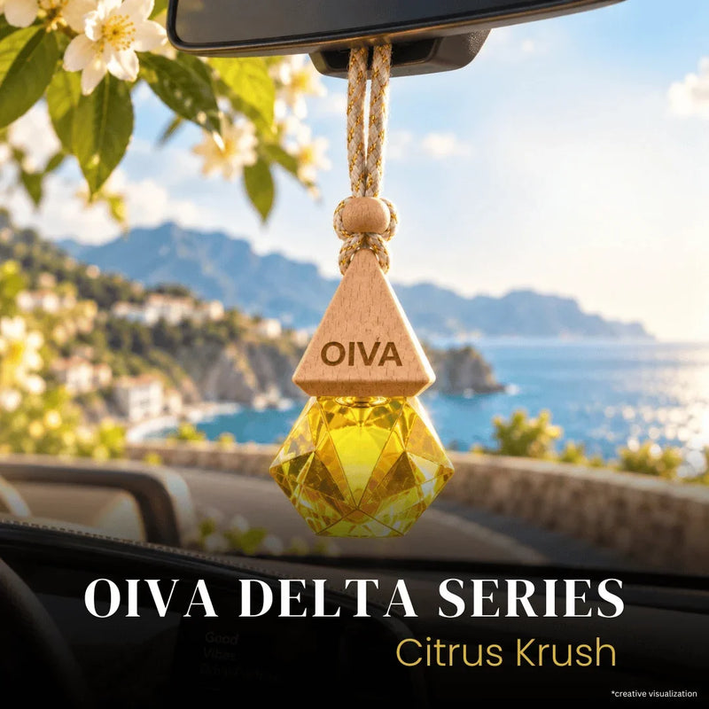 Oiva Delta Series Citrus Krush car air freshener hanging in a car window with a scenic coastal background. The product features a triangular wooden top engraved with 'OIVA' and a faceted yellow-green crystal lower section.