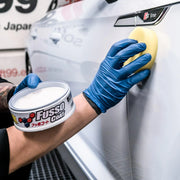 Hand applying Fusso Coat wax on white car door using sponge
