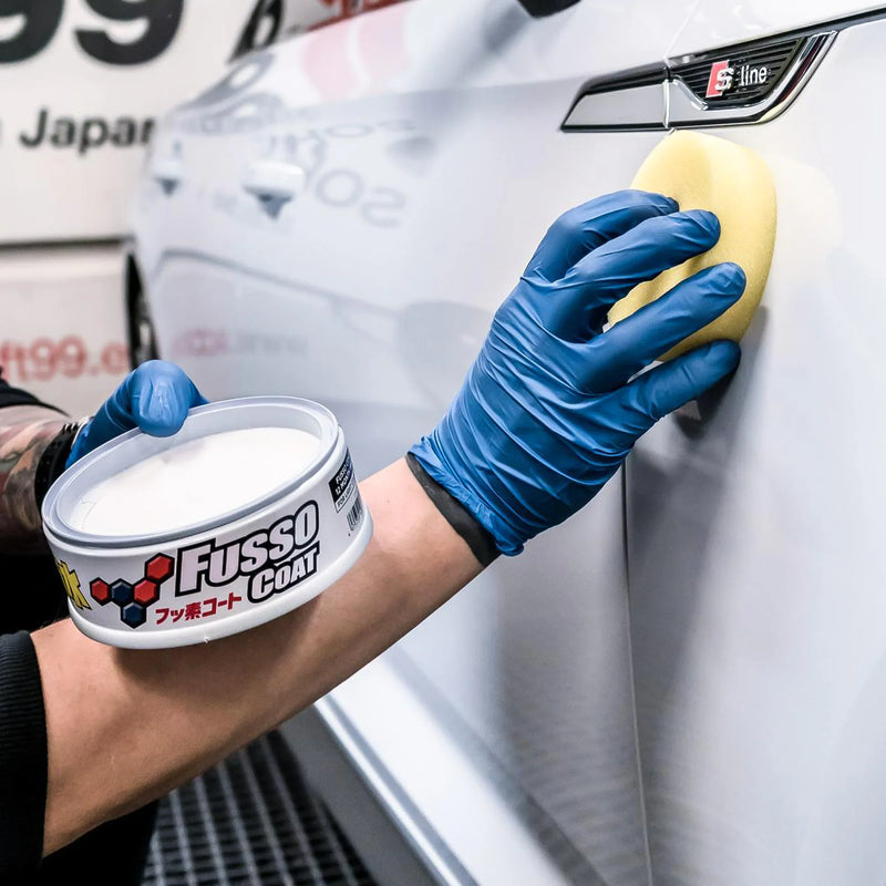 Hand applying Fusso Coat wax on white car door using sponge
